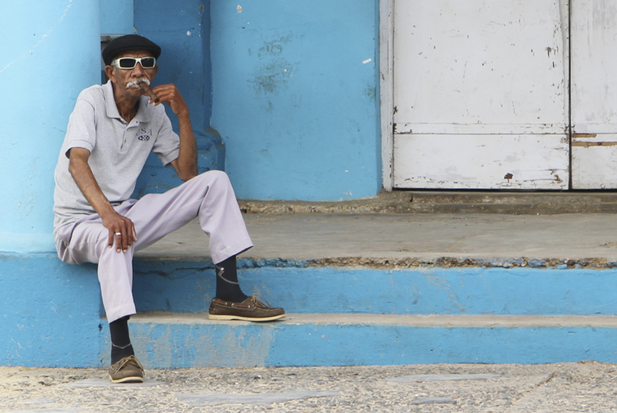 Man Sitting on Blue Porch - A Portrait of Cuba